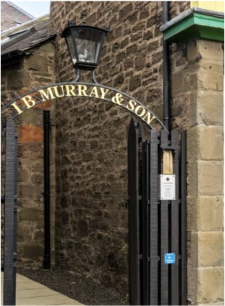 Wrought-iron 'I. B. Murray & Son' sign arched over the gated entrance to the firm's Dundee premises